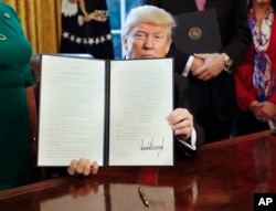 FILE - President Donald Trump holds up an executive order in the Oval Office of the White House, Feb. 3, 2017. The executive order directed the Treasury secretary to review the 2010 Dodd-Frank financial oversight law.