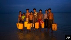 Newly arrived Rohingya Muslims carry the yellow plastic drums they used as flotation aids and listen to Bangladeshi authorities, not pictured, after swimming across the Naf River at Shah Porir Dwip, Bangladesh, Nov. 5, 2017.