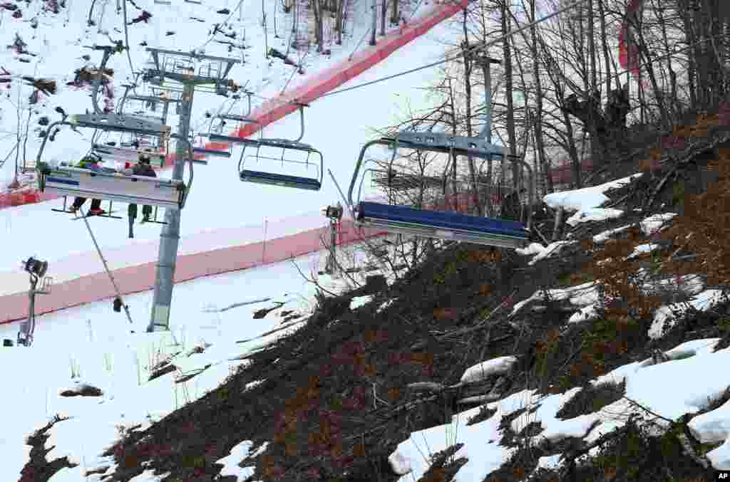 Salju dan tanah coklat terlihat dekat arena ski di Sochi. Cuaca hangat di pegunungan membuat salju terlalu lembek dan menyebabkan pembatalan latihan ski nomor putri, Selasa (11/2). (AP/Alessandro Trovati)