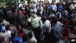 A police colonel talks with a group of Iranian workers during their protest in front of the Industrial Ministry building in Tehran, Iran, demanding their delayed salaries. (AP Photo)