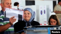 A Kosovo Albanian woman places her ballot paper into a voting box at the polling station in the capital city Pristina, June 8, 2014. 