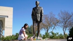 Thu Ton, de Dallas, coloca flores en la base de una estatua del ex presidente George H.W. Bush, tras su fallecimiento a los 94 años el 30 de noviembre de 2018.