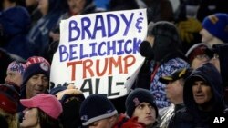 FILE - A New England Patriots fan holds a sign referring to Patriots quarterback Tom Brady, head coach Bill Belichick and President Donald Trump during the first half of the AFC championship NFL football game between the Patriots and the Pittsburgh Steelers in Foxborough, Mass., Jan. 22, 2017.