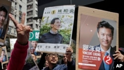 Supporters of Hong Kong pro-Beijing by-election candidate Vincent Cheng Wing-shun and pro-democracy by-election candidate Edward Yiu, show their promotional posters during an election campaign in Hong Kong, March 11, 2018. 