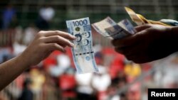 A gambler who lost a cockfighting bet, pays his wager inside an arena in Angeles city, north of Manila, Philippines March 11, 2015. 