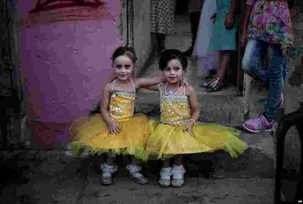 Two girls sit in front of the family house during the wedding party of Palestinian groom Saed Abu Aser, in Gaza City.