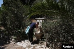 Una turista se refresca en una fuente mientras visita el sitio arqueológico del Templo de Zeus en Atenas, Grecia, el 4 de julio de 2019. ERRORES / Costas Baltas.