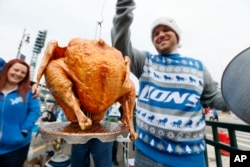 Brent Clodgio checks a Thanksgiving turkey while tailgating before an NFL football game between the Detroit Lions and Chicago Bears in Detroit, Nov. 27, 2014.