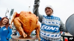 FILE - Brent Clodgio checks a Thanksgiving turkey while tailgating before an football game in Detroit in 2014. "Tailgate" is a party you have in the parking lot of a big event such as a concert or football game.