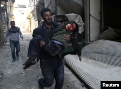 Seorang pria membopong anak laki-laki yang terluka di Kota Hamouriyeh, yang dikuasai dan dan dikepung pemberontak di timur Ghouta, dekat Damaskus, Suriah, 21 Februari 2018.