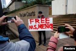 FILE - A man holds a sign outside of the B.C. Supreme Court bail hearing of Huawei CFO Meng Wanzhou, who is being held on an extradition warrant in Vancouver, British Columbia, Canada, Dec. 10, 2018.