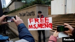 FILE - A man holds a sign outside of the B.C. Supreme Court bail hearing of Huawei CFO Meng Wanzhou, who is being held on an extradition warrant in Vancouver, British Columbia, Canada Dec. 10, 2018. 