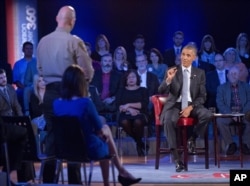 President Barack Obama answers questions from Arizona Sheriff Paul Babeu, standing at left, during a CNN televised town-hall meeting at George Mason University in Fairfax, Va., Jan. 7, 2016.