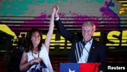 El candidato presidencial chileno José Antonio Kast y su esposa Maria Pia Adriasola Barroilhet levantan la mano mientras habla después de los resultados parciales de la primera vuelta durante las elecciones presidenciales, en Santiago, Chile, 21 de noviembre de 2021.