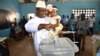 Sierra Leone's People Party presidential candidate Julius Mada Bio holds his daughter while casting his ballot for the general elections, at a polling station in Freetown, March 7, 2018, as his wife looks on.