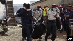 Rescue workers carry bodies at the site of a plane crash in Lagos, Nigeria, June 4, 2012.