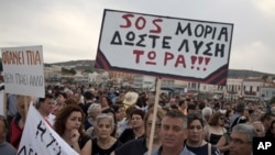 FILE - Protesters hold a placard that reads in Greek, "SOS Moria. Solution now," referring to the Moria refugee camp, during a protest in the town of Mytilene on the northeastern Aegean island of Lesbos, May 3, 2018. 
