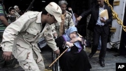 A rebel helps an elderly evacuee Libyan woman on a wheelchair disembarking the Albanian ferry Red Star 1 that evacuated injured people and refugees fleeing the battered city of Misrata, after docking at the port of Benghazi, Libya, April 28, 2011