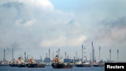 FILE - Ships are seen anchored in front of a refinery on Singapore's Bukom Island, July 6, 2014.