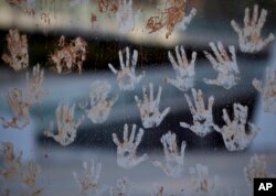 Mud hand prints are seen on a glass window, during a protest at the door of the Brazilian mining company Vale, in Rio de Janeiro, Brazil, Jan. 28, 2019.