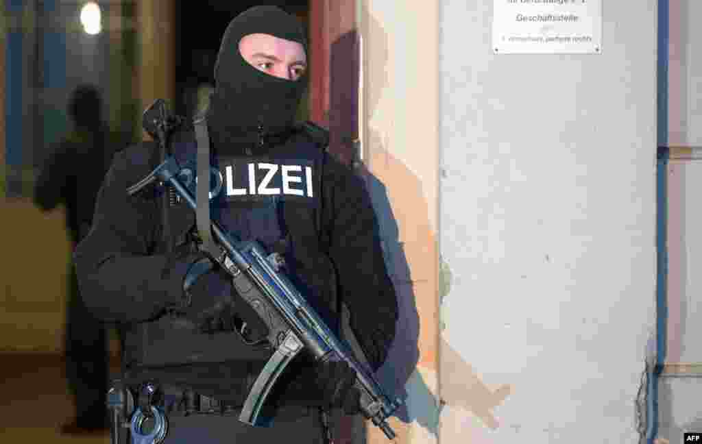 A German police officer stands outside a Berlin apartment building where a raid against suspected jihadists took place, Jan. 16, 2014.