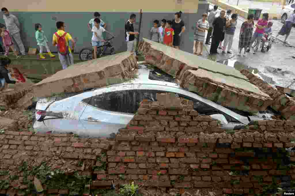중국 랴오닝성 선양에 폭우가 내린 뒤 무너진 담벼락 아래 차량이 깔려있다.