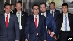 U.S. Treasury Secretary Steven Mnuchin, center, escorted by bodyguards and a delegation leaves a hotel in Beijing, March 29, 2019. 