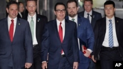 Menteri Keuangan AS Steven Mnuchin (tengah) dikawal oleh para pengawalnya dan delegasi meninggalkan hotel di Beijing, 29 Maret 2019.
