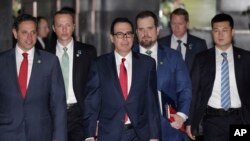 U.S. Treasury Secretary Steven Mnuchin, center, escorted by bodyguards and a delegation leaves a hotel in Beijing, Friday, March 29, 2019. 