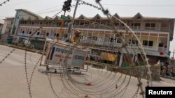 An Indian policeman stands guard behind concertina wire during a general strike in Srinagar, June 25, 2013.