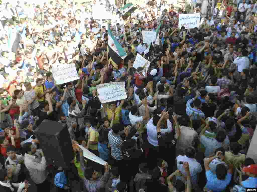 Demonstrators hold opposition flags and banners during a protest against Syria's President Bashar al-Assad after Friday prayers in Houla near Homs October 19, 2012.