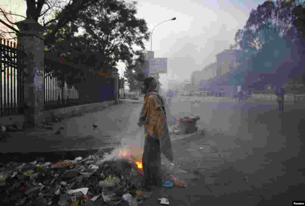 کھٹمنڈو میں ایک بے گھر شخص سرد موسم میں ایک جلتے ہوئے ڈھیر کے پاس کھڑا ہے۔