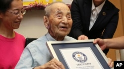 Yasutaro Koide, 112, receives the Guinness World Records certificate as he is formally recognized as the world's oldest man at a nursing home in Nagoya, central Japan, Aug. 21, 2015.