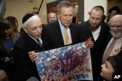Republican presidential candidate, Ohio Gov. John Kasich, looks at a picture of the White House made by students at a religious school in the Brooklyn borough of New York, April 12, 2016.