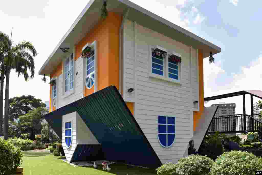 A tourist takes pictures outside the Kuala Lumpur Upside Down House at KL Tower in Malaysia.