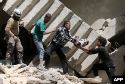 Syrian civil defense volunteers and rescuers remove a baby from under the rubble of a destroyed building following a reported air strike on the rebel-held neighbourhood of al-Kalasa in the northern city of Aleppo, April 28, 2016.