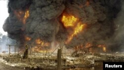 La fumée et les flammes s’échappent d'un pipeline de pétrole en feu après un sabotage par des hommes armés non identifiés à Andoni, Rivers State, Nigeria, 20 décembre 2005. 