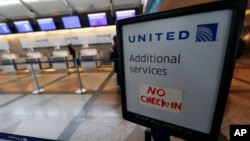 FILE - A piece of tape is affixed to a sign marking an empty line at the United Airlines ticket counter at Denver International Airport, April 16, 2016, in Denver, Colorado.