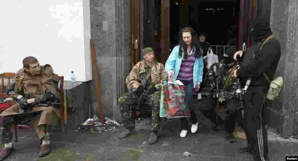 Uma mulher sai da sede do Governo regional enquanto pró-russos armados estão sentados à entrada, em&nbsp; Luhansk, Abril 30, 2014.