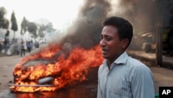 Một người đàn ông than khóc sau khi xe của ông bị các nhà hoạt động đảng Jamaat-e-Islami đốt cháy tại thủ đô Dhaka.