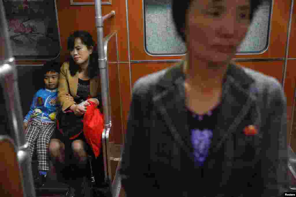 지하철 역 안에서 한 소년이 어머니 팔을 붙잡고 앉아 있다.