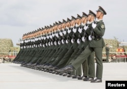 FILE - Soldiers of China's People's Liberation Army march with their weapons during a training session for a military parade to mark the 70th anniversary of the end of World War II, at a military base in Beijing, Sept. 1, 2015.