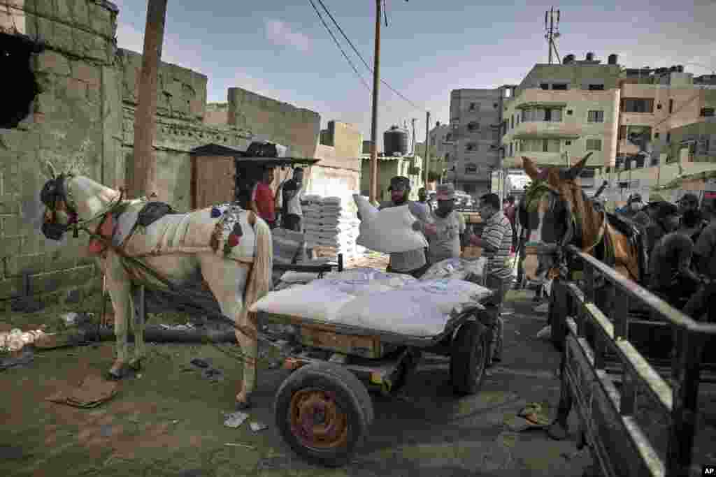 A Palestinian man loads a horse cart with sacks of flour received from the UN Relief and Works Agency, (UNRWA), at a warehouse in Gaza City, Wednesday, Sept. 30, 2020. (AP Photo/Khalil Hamra)