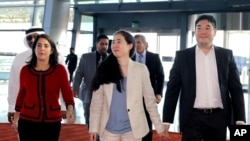 American couple Grace, center, and Matthew Huang, right, walk to their departure gate with U.S. Ambassador to Qatar, Dana Shell Smith, left, at the Hamad International Airport in Doha, Qatar, Dec. 3, 2014.