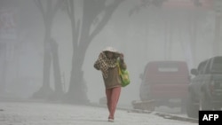 Seorang warga berjalan di bawah hujan abu menyusul letusan baru dari Gunung Sinabung yang mempengaruhi kabupaten Karo dan daerah-daerah di Sumatra Utara lainnya (17/9). 