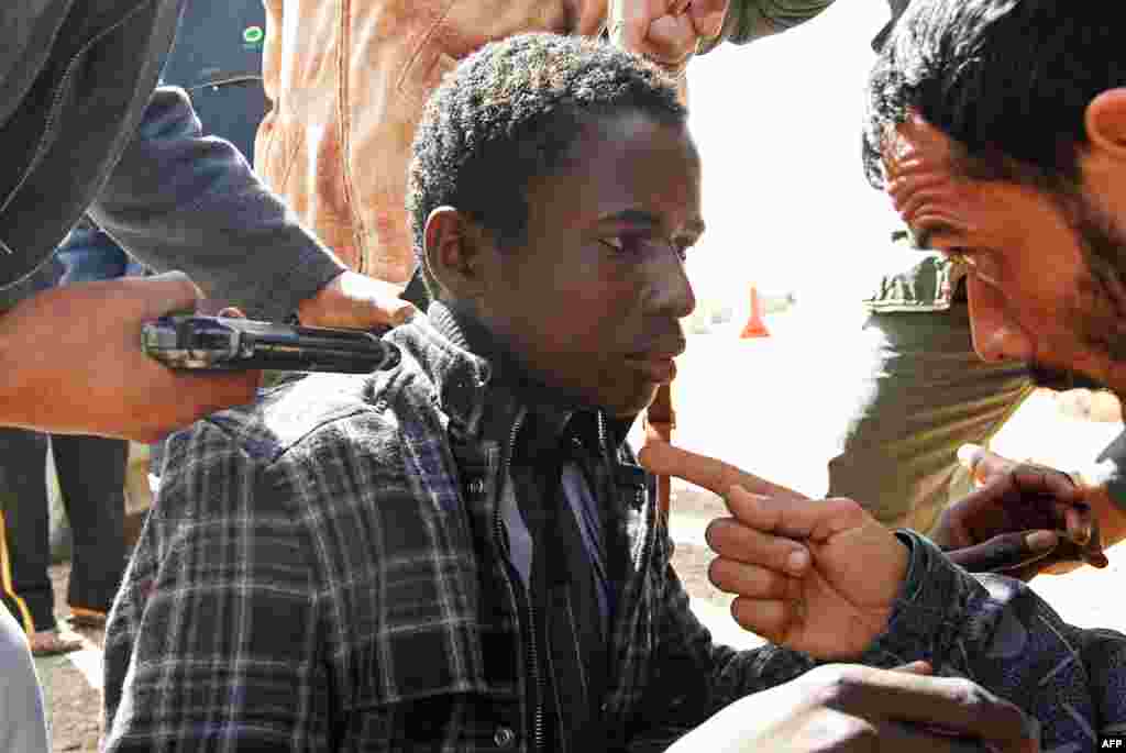 Rebels hold a young man at gunpoint, who they accuse of being a loyalist to Libyan leader Moammar Gadhafi, March 3, 2011. (Reuters)