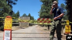 Matt Engbring, a fire prevention officer with the U.S. Forest Service, checks on signs that alert the public to closures in parts of the national forest surrounding Flagstaff, Ariz., May 24, 2018.