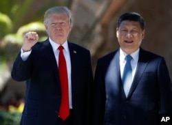 President Donald Trump and Chinese President Xi Jinping pause for photographs at Mar-a-Lago, Friday, April 7, 2017, in Palm Beach, Fla.