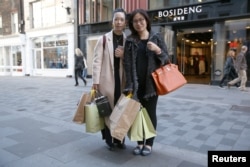 FILE - Chinese tourists Haiti Chen, left, and Jialin Wang pose for a portrait in London, Oct. 5, 2016.