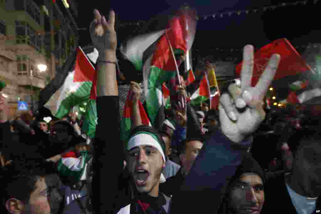 Palestinians celebrate as they watch a screen showing the U.N. General Assembly vote on a resolution to upgrade the status of the Palestinian Authority to a non-member observer state, in the West Bank city of Ramallah, Nov. 29, 2012. 